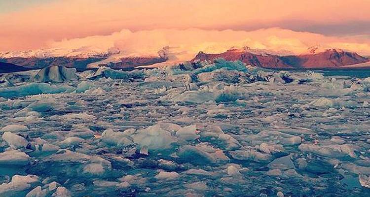 Lac gelé avec des icebergs éparpillés sous un ciel coloré.