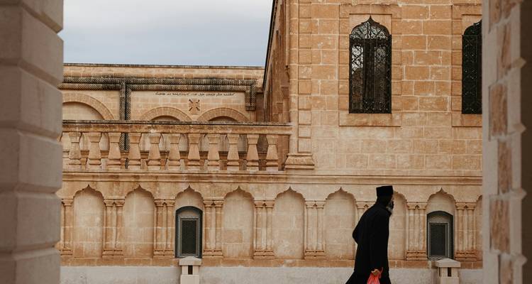 Personne marchant devant un bâtiment traditionnel en pierre.