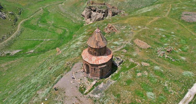 Vue aérienne d'une tour ronde historique sur une colline verte.