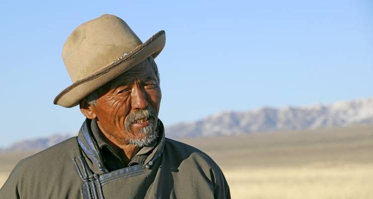 A portrait of a person in traditional clothing with a vast landscape.