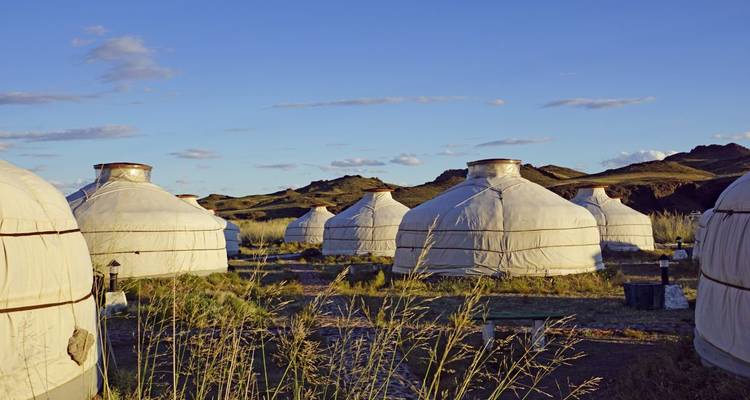 Multiple yurts set in a scenic landscape with hills.