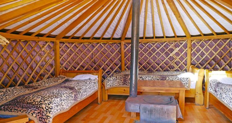 Interior of a yurt with beds and a stove.