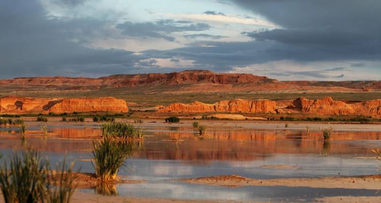 Scenic landscape with sandstone formations and water reflections.