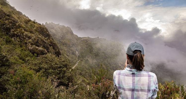 Person taking a photo of a misty mountain landscape.