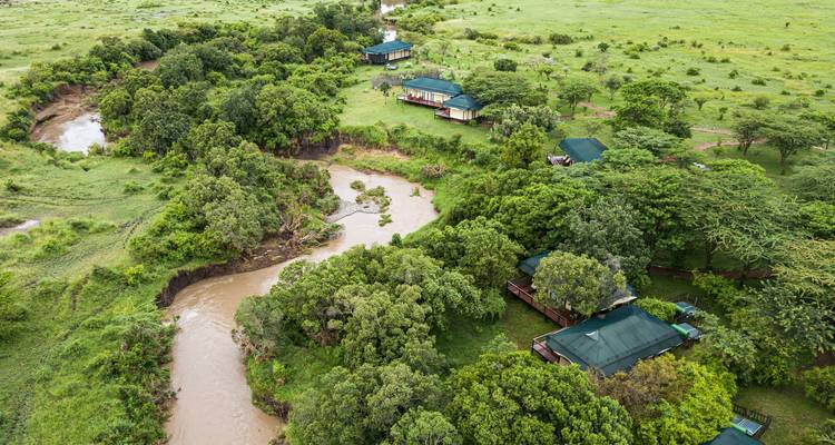 Luftaufnahme von Lodges an einem Fluss in üppiger Landschaft