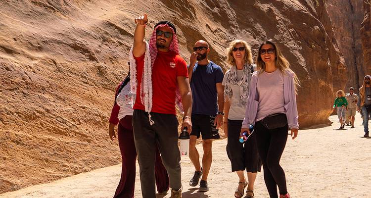 Le guide conduit les voyageurs à travers l'étroit siq de grès de Pétra, en signalant les caractéristiques.