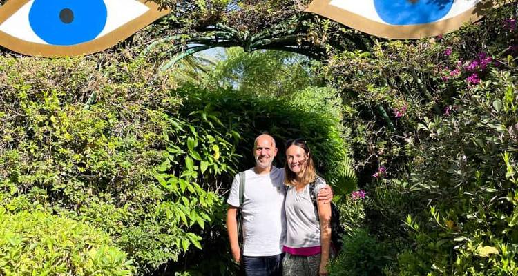 A couple posing under a decorative arch with green foliage.