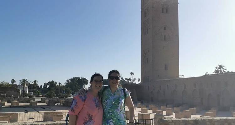 Two women posing in front of a large tower and open courtyard.