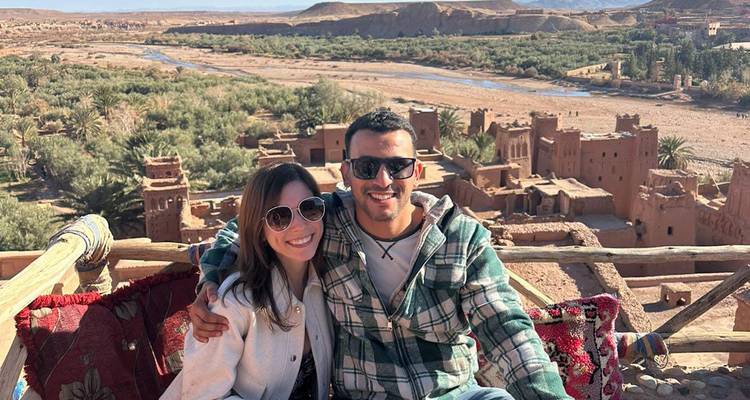 A couple posing with an ancient fortress and landscape.