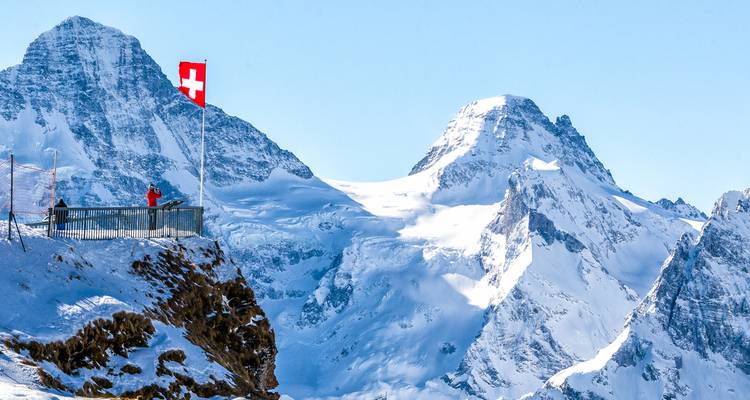 Alpes suisses avec un drapeau suisse sur une plateforme d'observation.