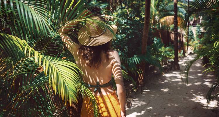 Vrouw die door een pad loopt omringd door weelderig gebladerte.