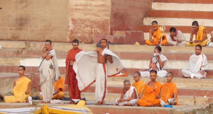 Junge Männer in traditioneller Kleidung führen Rituale auf Stufen durch.