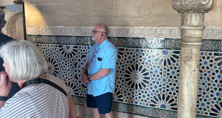 Homme debout devant des carreaux complexes et des colonnes.