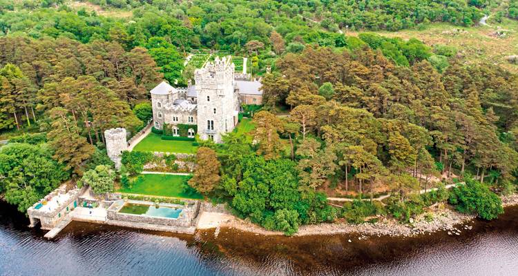 Vue aérienne d'un château entouré d'une végétation luxuriante.