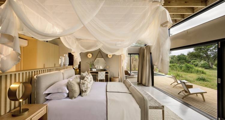 Interior de dormitorio lujoso con decoración elegante y ventanas grandes.