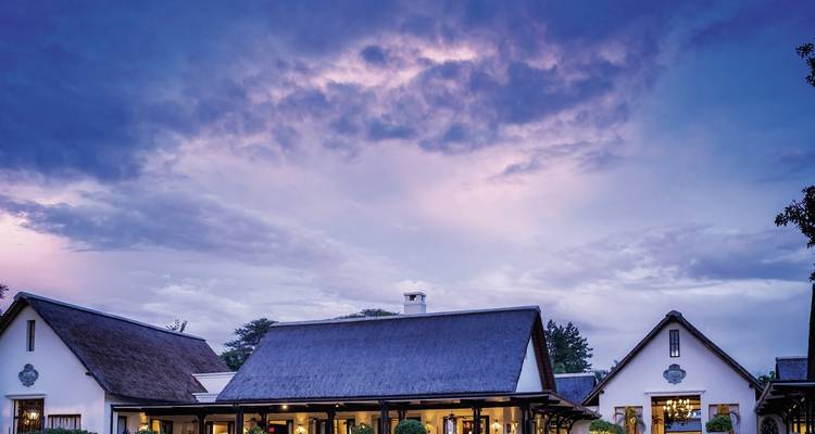 Casa tradicional rodeada de un paisaje pintoresco al anochecer.