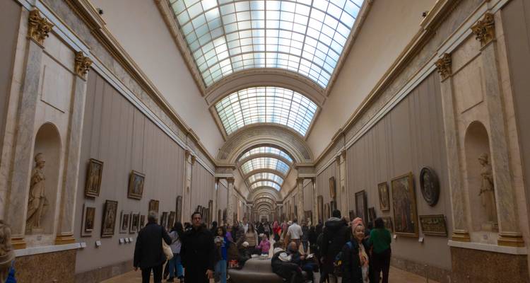 Long couloir d'un musée avec des peintures et des gens.