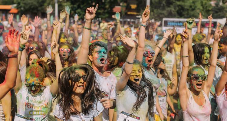 Groupe de personnes célébrant un festival de couleurs avec des couleurs vives sur leurs visages et leurs vêtements.