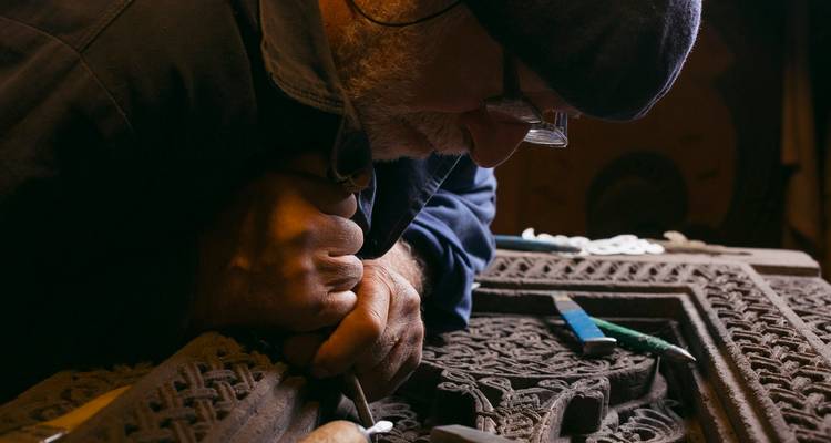 Une personne sculptant des motifs complexes dans un morceau de bois.