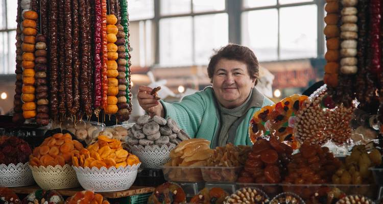 Femme souriante à un étal de marché avec des fruits secs et des bonbons.