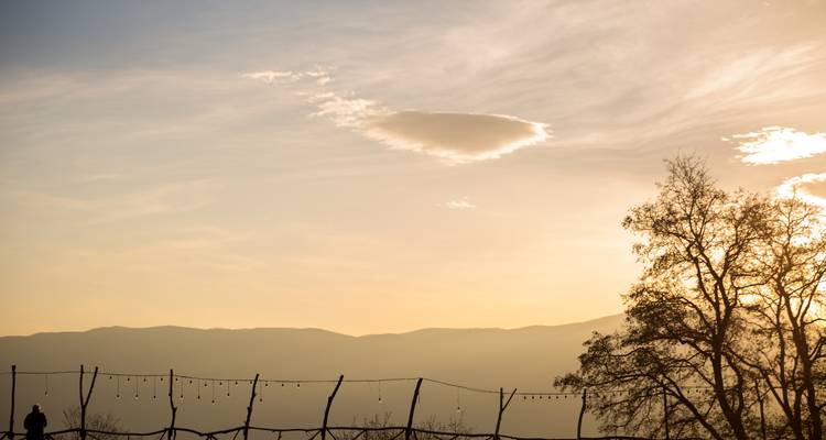 Vue du coucher de soleil avec montagnes, arbres et éclairage décoratif.