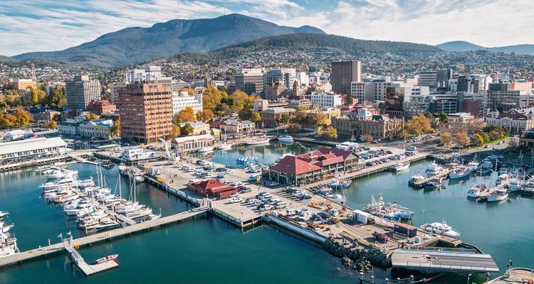 Aerial view of a city by the water with boats and mountains.