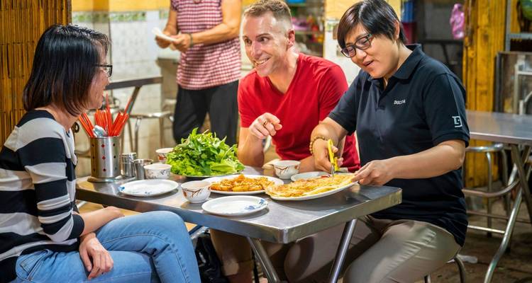 Groupe de personnes dînant dans un lieu de nourriture de rue.
