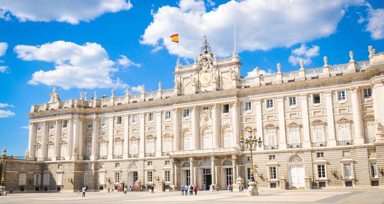 La gran fachada del Palacio Real de Madrid con visitantes en la amplia plaza de abajo.