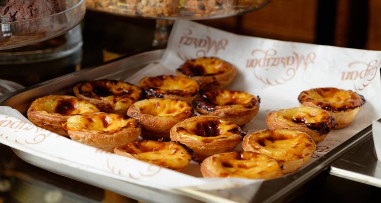 Bandeja de pastéis de nata recién horneados enfriándose en papel de horno.