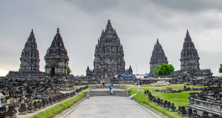 The towering stone spires of Prambanan Temple complex under a grey sky.