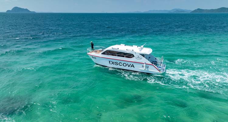 Un bateau naviguant sur des eaux bleues claires avec des îles en arrière-plan.