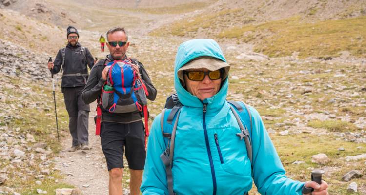 Eine Gruppe von Wanderern mit Rucksäcken, die auf einem steinigen Pfad entlanggehen.