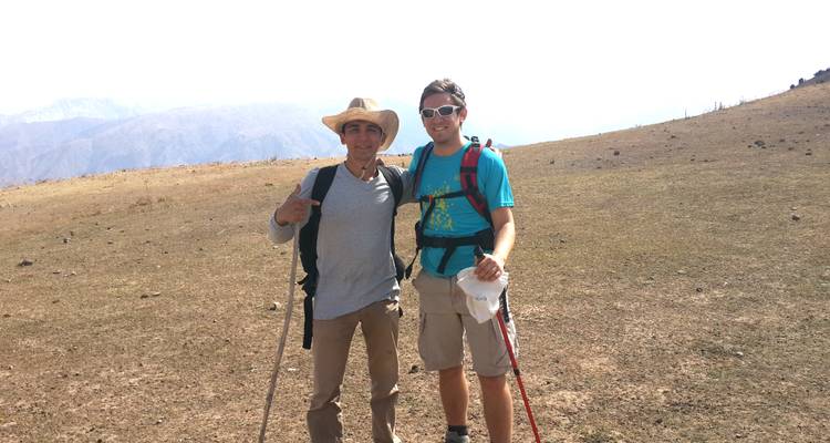 Zwei Wanderer posieren auf einem Hügel mit Blick über die Berge.