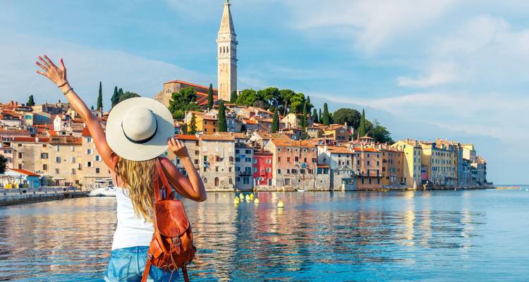 Woman facing picturesque coastal town with vibrant houses and architecture.