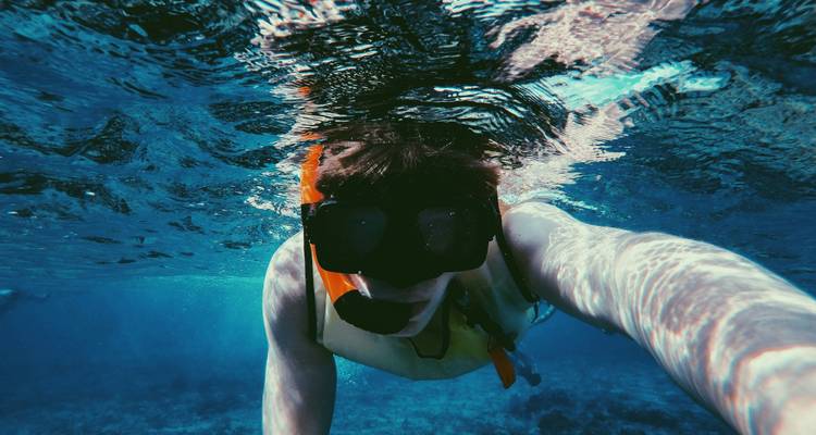 Persona haciendo snorkel bajo el agua, tomándose una selfie.