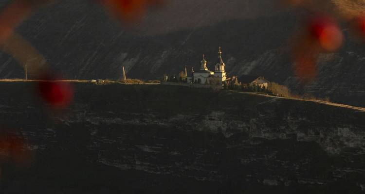 Remote hilltop monastery bathed in warm sidelighting, viewed from afar.