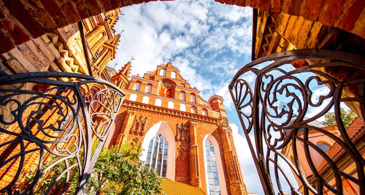 Blick auf eine Kathedrale aus rotem Backstein mit kunstvollen Eisentoren.