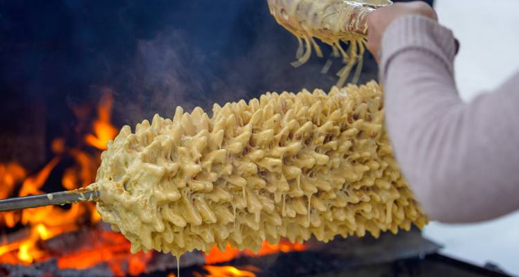 Nahaufnahme eines traditionellen litauischen Baumkuchens, der über einem Feuer gebacken wird.