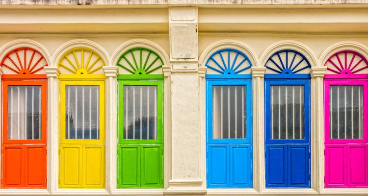 Bunte regenbogenfarbene Fenster an einer Gebäudefassade.
