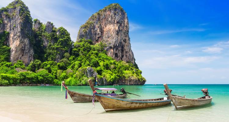 Longtail-Boote an einem malerischen Strand in Krabi, Thailand.