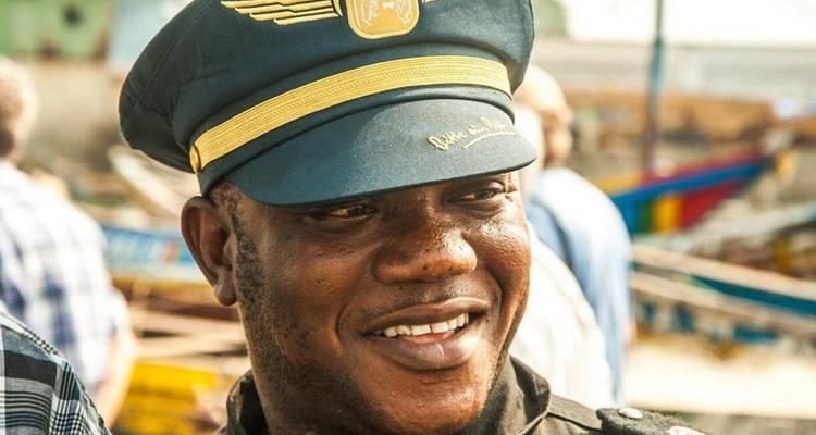 Homme souriant en uniforme sur un arrière-plan de bateaux.