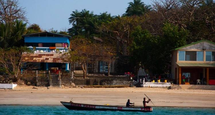 Deux personnes dans un canoë près d'un rivage tropical.