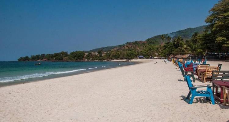 Plage de sable avec des chaises colorées and eau claire.