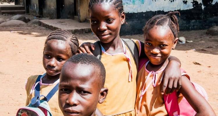Des enfants posant joyeusement devant un bâtiment scolaire.