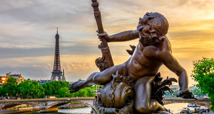 Estatua con vista de la Torre Eiffel y el río Sena al atardecer.