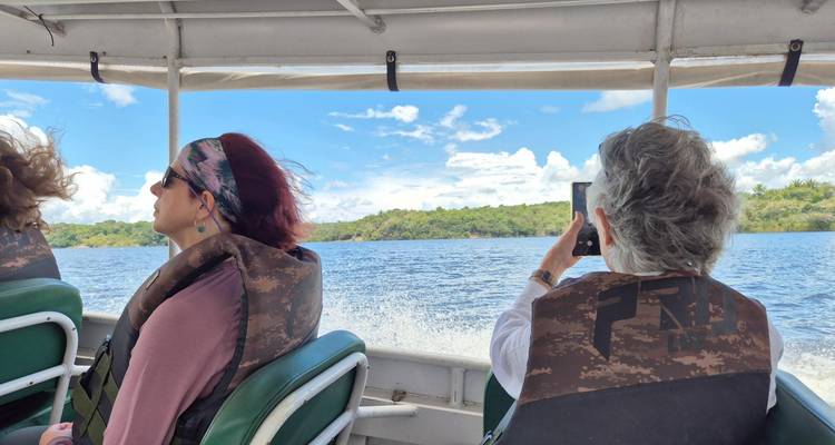 Travellers in lifejackets speed across a wide Amazon river in an open motorboat.