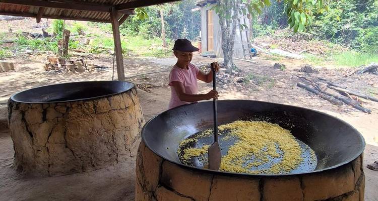 Local woman stirs cassava in a huge clay-lined iron pan in an Amazon village.