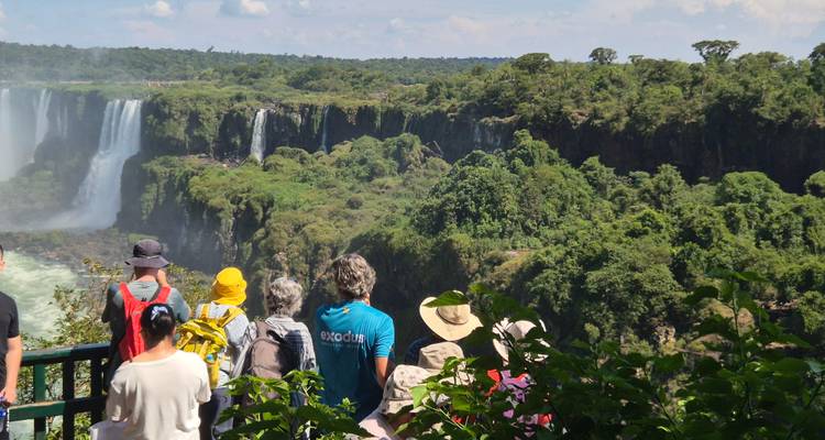 Tour group enjoys a panoramic view of Iguazu Falls framed by lush jungle.