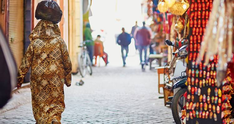 Eine Person in traditioneller Kleidung, die durch einen bunten Markt geht.