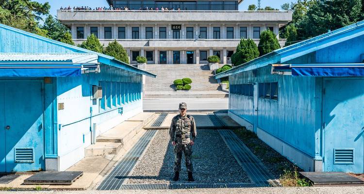 South Korean soldier stands guard between the distinctive blue UN buildings at the DMZ joint security area.